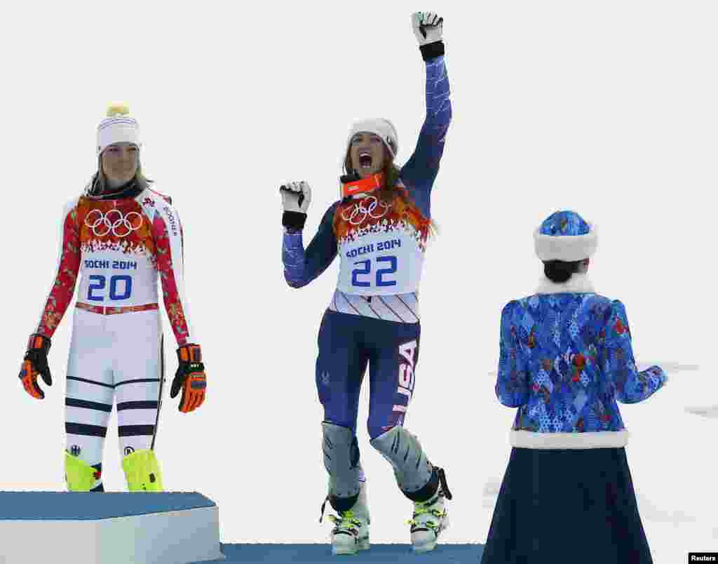 Third-placed Julia Mancuso of the United States celebrates on the podium in front German winner Maria Hoefl-Riesch (left) during the flower ceremony after the women&#39;s alpine-skiing super-combined event at the Rosa Khutor Alpine Center. Hoefl-Riesch won her second straight Olympic super-combined title, beating Nicole Hosp of Austria and Mancuso.
