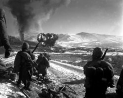 Удар с воздуха по позициям коммунистов в декабре 1950 года. Морские пехотинцы США смотрят на облако после удара.