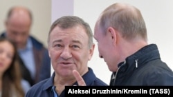 Russian President Vladimir Putin (right) speaks with Arkady Rotenberg as they attend the opening ceremony for a bridge linking Ukraine's Crimean Peninsula to Russia in May 2018. 