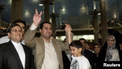 Shahram Amiri flashes the victory sign as he arrives at the Imam Khomeini Airport in Tehran.