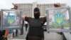 A masked pro-Russian separatist carries two ballot boxes from a seized polling station in Donetsk, Ukraine.