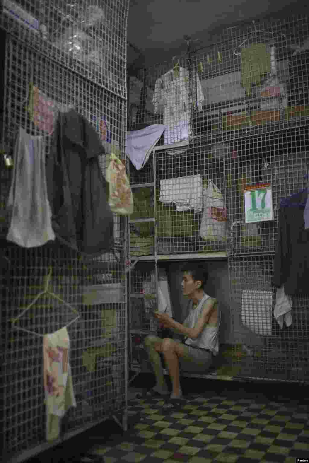 A man burns incense while sitting in a &quot;cage home&quot; in Hong Kong&#39;s Tai Kok Tsui district in 2008.