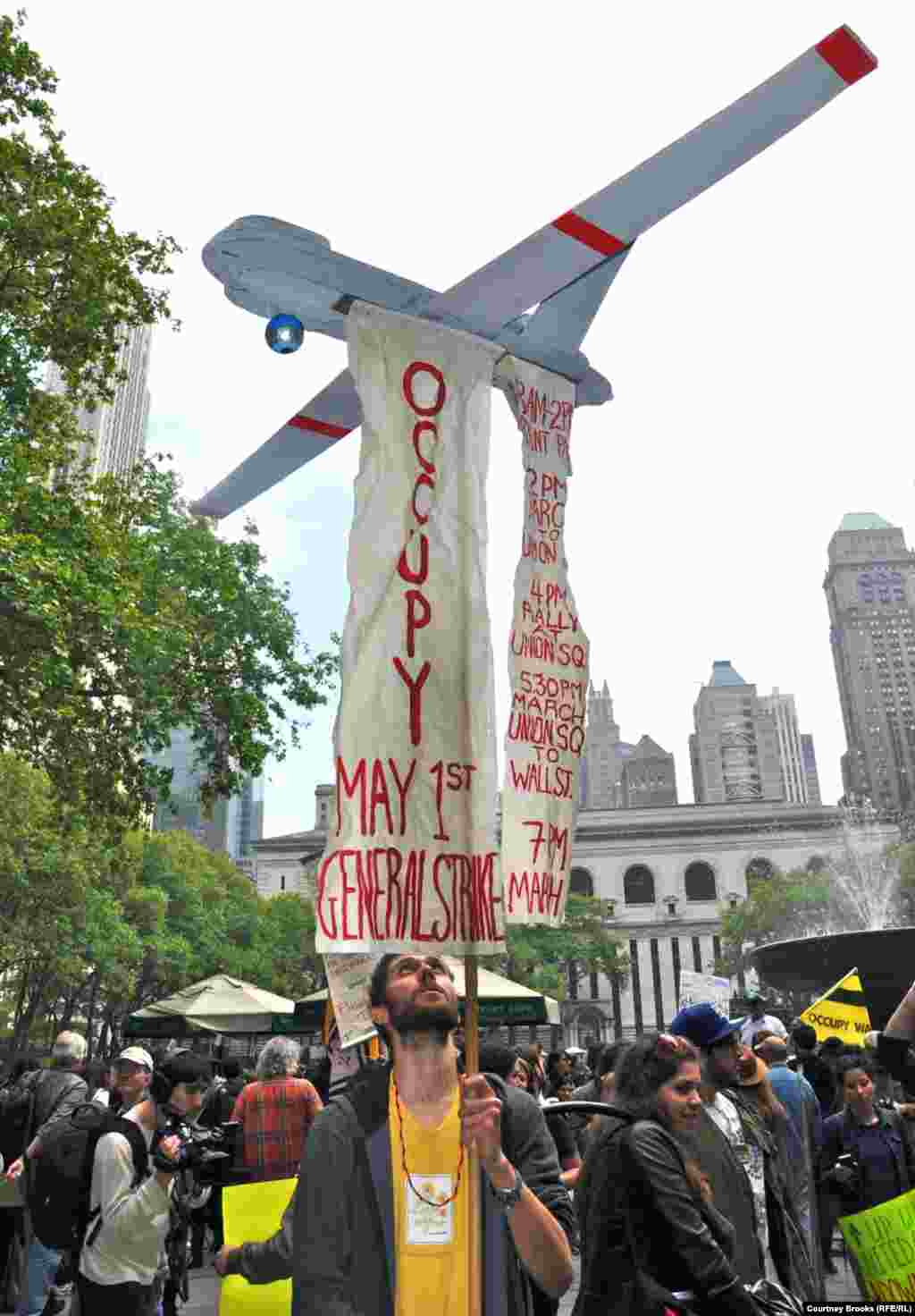 A protester carries an airplane from which hangs the OWS movement&#39;s agenda for May 1.