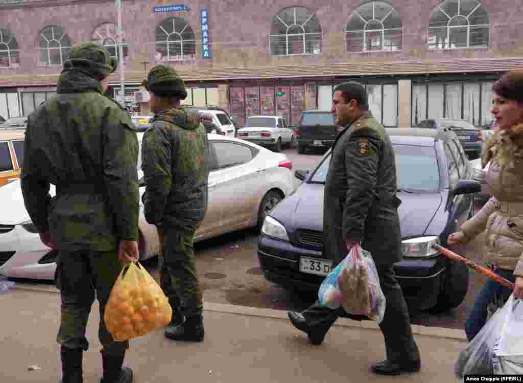 An Armenian Army officer (right) walks past Russian soldiers in Gyumri&#39;s center. The officer made eye contact with the soldiers, but no greetings were exchanged.