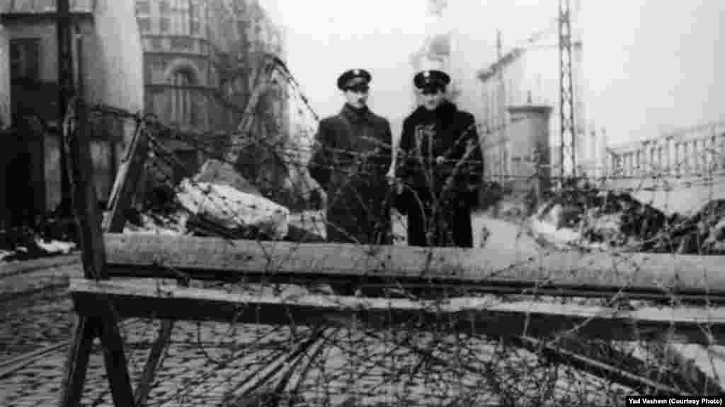Двама еврейски полицаи край заграждения с бодлива тел във Варшавското гето. Снимка: Дж. Дж. Хайдекер