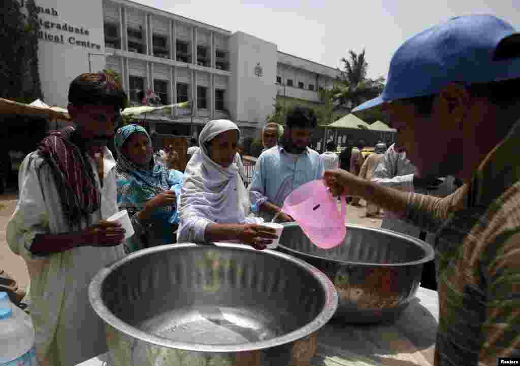 People receive drinking water from volunteers during the intensely hot weather in Karachi on June 23.