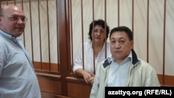 Юрист Наталья Соколова за решеткой в зале суда. Слева от нее - муж Василий Чепурной, справа адвокат Арман Жаменов. Актау, 26 сентября 2011 года.