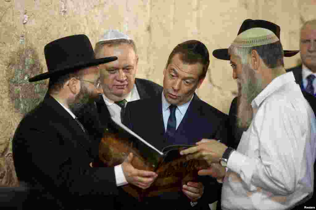 Russian Prime Minister Dmitry Medvedev (center) looks into a book presented to him during a visit to the Western Wall in Jerusalem on November 10. (Reuters/Dan Balilty)