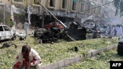 A victim of the Peshawar suicide bombing awaits assistance as people scour the site for other injured countrymen.