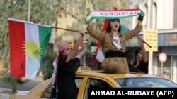 Iraqis Kurdish women celebrate with the Kurdish flag as they ride outside the windows and roof of a taxi in the northern city of Kirkuk on September 25, 2017 as they voted in a referendum on independence.