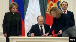 Russian President Vladimir Putin's (center) critics and civil-liberties activists have long accused the authorities of using counterterrorism and extremism laws to target the Kremlin's political opponents, and they say the new law threatens a dramatic escalation of this strategy.
