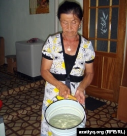 Жительница села Шубарши Умсынай Кудиярова показывает ведро воды.
