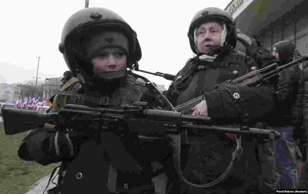 An elderly woman and a boy pose with assault rifles during celebrations of Russia&#39;s Defender of the Fatherland Day in Simferopol on the Ukrainian peninsula of Crimea on February 23. (Reuters/Pavel Rebrov)