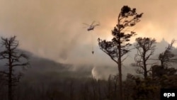 An image released by the Russian Emergency Situations Ministry on August 12 shows a helicopter dropping water onto a forest fire in the Baikal lake area in Irkutsk. 