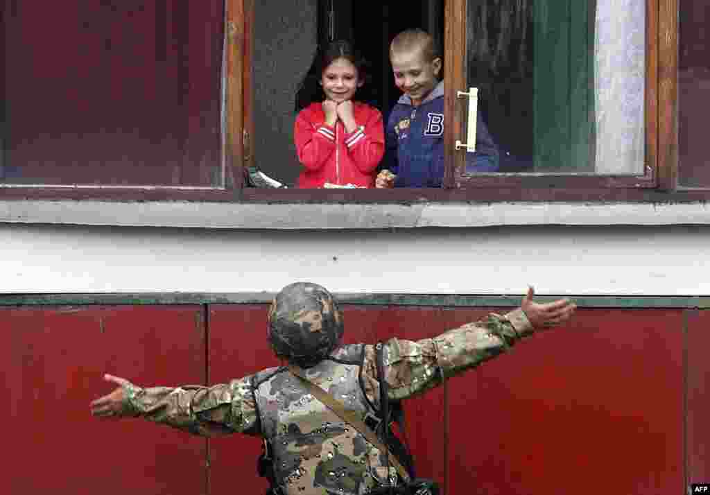 A Ukrainian soldier gestures as he talks with children on August 18 in the small eastern city of Popasna in the Luhansk Region. (AFP/Anatolii Stepanov)