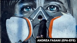 Një person me maskë mbrojtëse duke ecur rrugëve të Italisë.