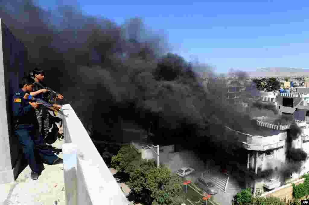 Afghan policemen stand guard on a rooftop as smoke rises following an attack by insurgents on the Indian Consulate in Herat on May 23. (AFP/Aref Karimi)