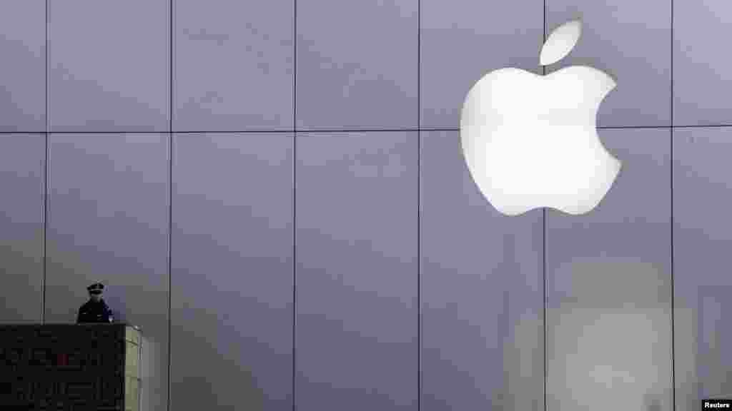 A policeman looks out from a balcony as the crowd is dispersed from the front of an Apple store in Beijing. Sales of the iPhone 4S caused a near-riot in one of Apple&#39;s Beijing retail stores. (Photo by David Gray for Reuters)