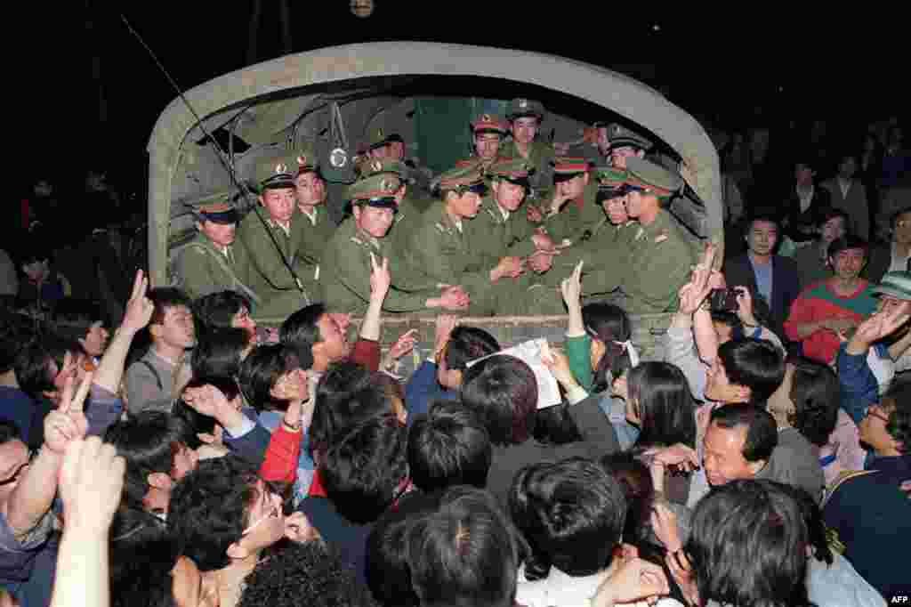 Demonstrators raise their fists and flash victory signs as they stop a military struck on its way to Tiananmen Square shortly after martial law was declared on May 20, 1989.