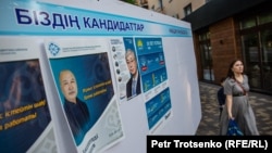Кезектен тыс президент сайлауына түскен кандидаттардың сайлау жарнамасынан қасынан өтіп бара жатқан адам. Алматы, 14 мамыр 2019 жыл.