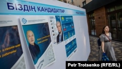 A woman walks past election posters of Kazakh presidential candidates Qasym-Zhomart Toqaev and Amangeldi Taspikhov. Almaty, 14May2019