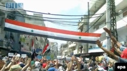 A video grab shows Syrian protesters waving a national flag in Latakia.
