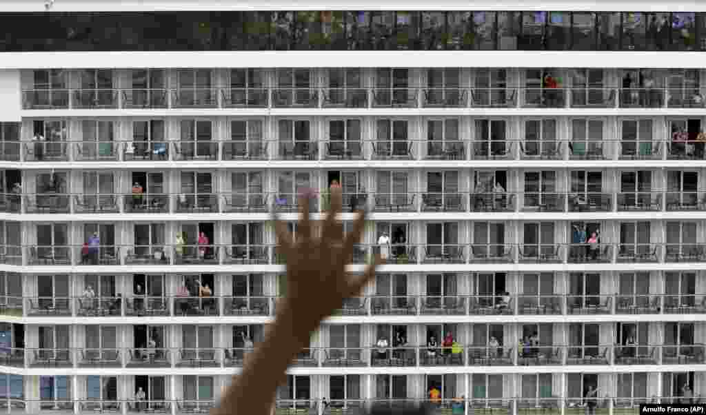 A tourist waves to passengers of the Norwegian Bliss from the Panama Canal Visitors Center as the ship makes its way through the canal, one of the largest ships to ever navigate it. Norwegian Bliss features 20 decks and a capacity of about 4,000 passengers. (AP/Arnulfo Franco)