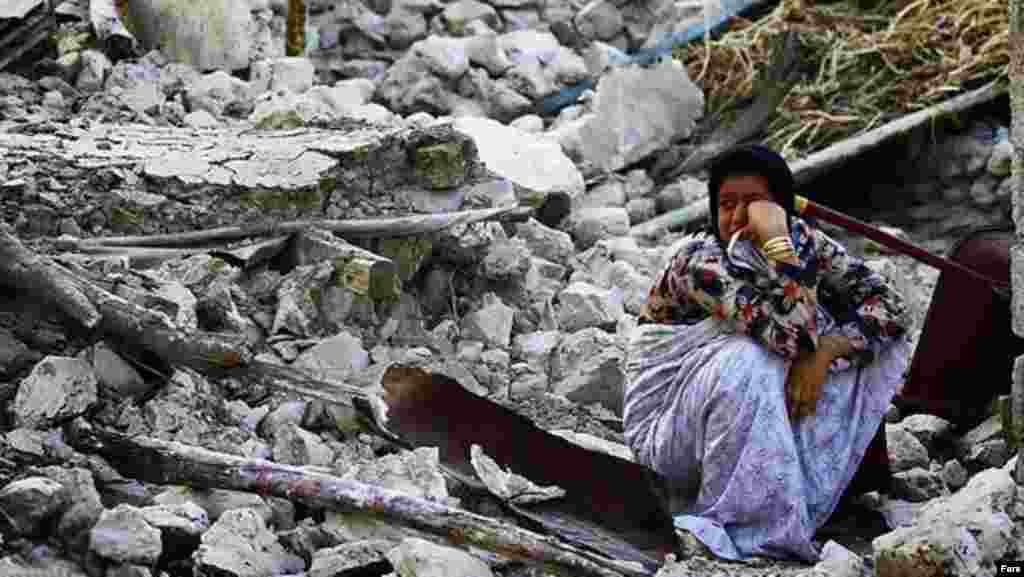 Iran -- An Iranian woman squats on her destroyed house in the town of Shonbeh, southeast of Bushehr after a powerful earthquake struck near the Gulf port city of Bushehr, 09Apr2013