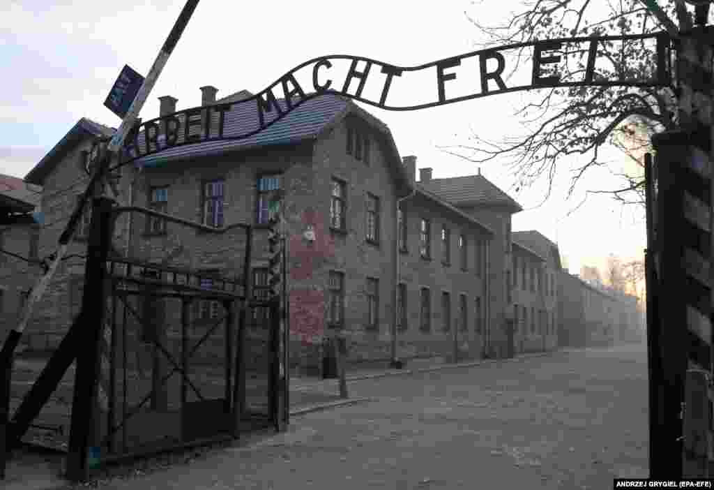 Ворота смерти, ведущие в лагерь Аушвиц-Биркенау. Циничная надпись над воротами сохранилась: &quot;Труд освобождает&quot;. Полные масштабы убийства людей в Освенциме были осознаны только после Второй мировой войны.&nbsp;&nbsp;