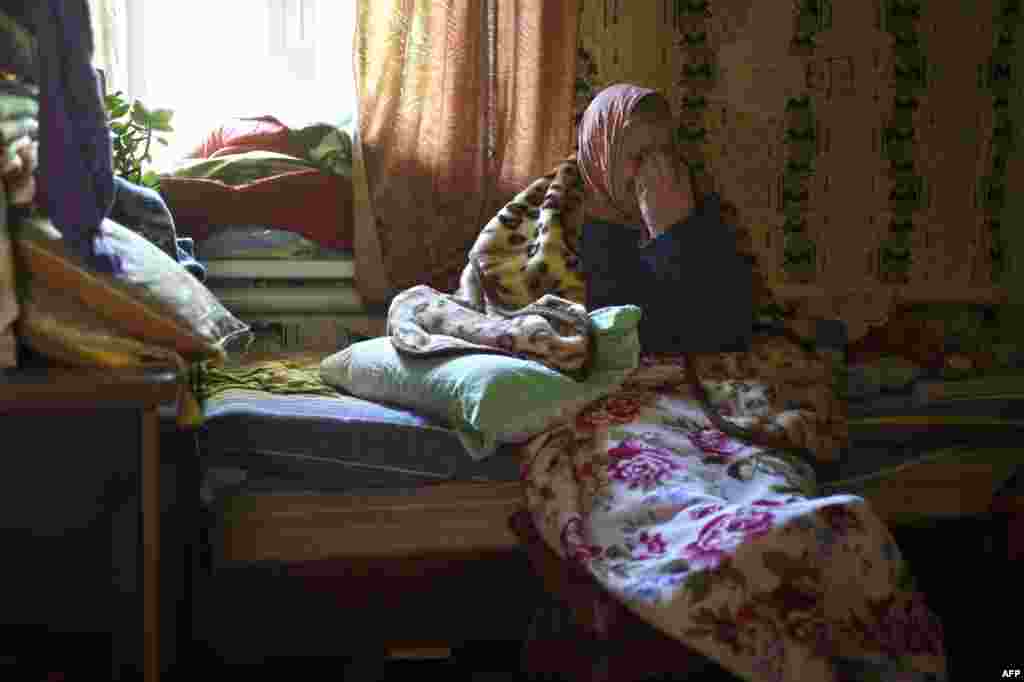 A&nbsp;woman cries as she sits on a bed in the Oktiabrskiy district of the rebel-held eastern Ukrainian city of Donetsk. At least four rockets hit three houses, killing one man living in the neighborhood, next to a cement factory occupied by pro-Russian militants. (AFP/Philippe Desmazes) 