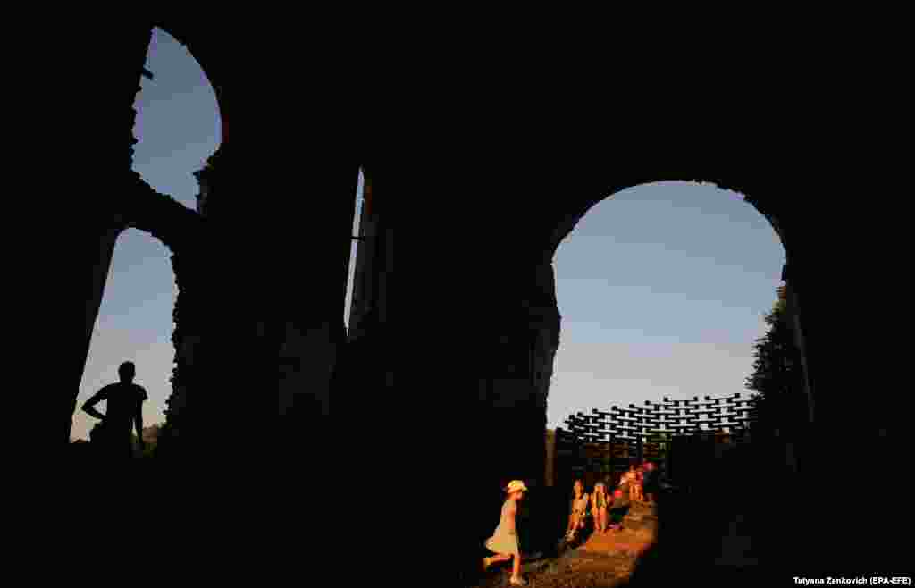 Minskden 160 km uzaklykdaky Beleýa serkow obasynda Sprawa festiwalynyň gün ýaşar uçurlarynda başlanjak konsertine garaşýan adamlar. People wait inside a church&#39;s ruins for a concert to start at sunset during the Sprava festival in the Belarusian village of Belaya Tserkov, some 160 kilometers from Minsk. (EPA-EFE/Tatyana Zenkovich)