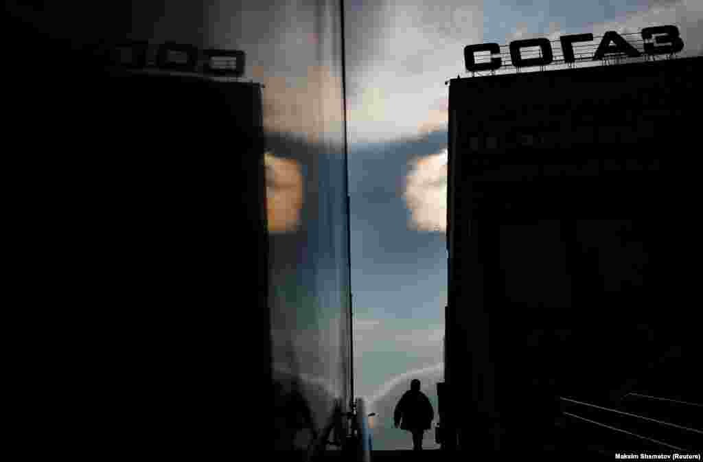 A man and the Sogaz insurance company's headquarters are reflected on the wall of an underpass in Moscow. (Reuters/Maxim Shemetov)