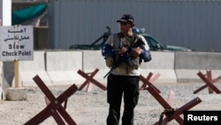 Сотрудник служб безопасности недалеко от места взрыва в кабульском аэропорту. 22 июля 2014 года.