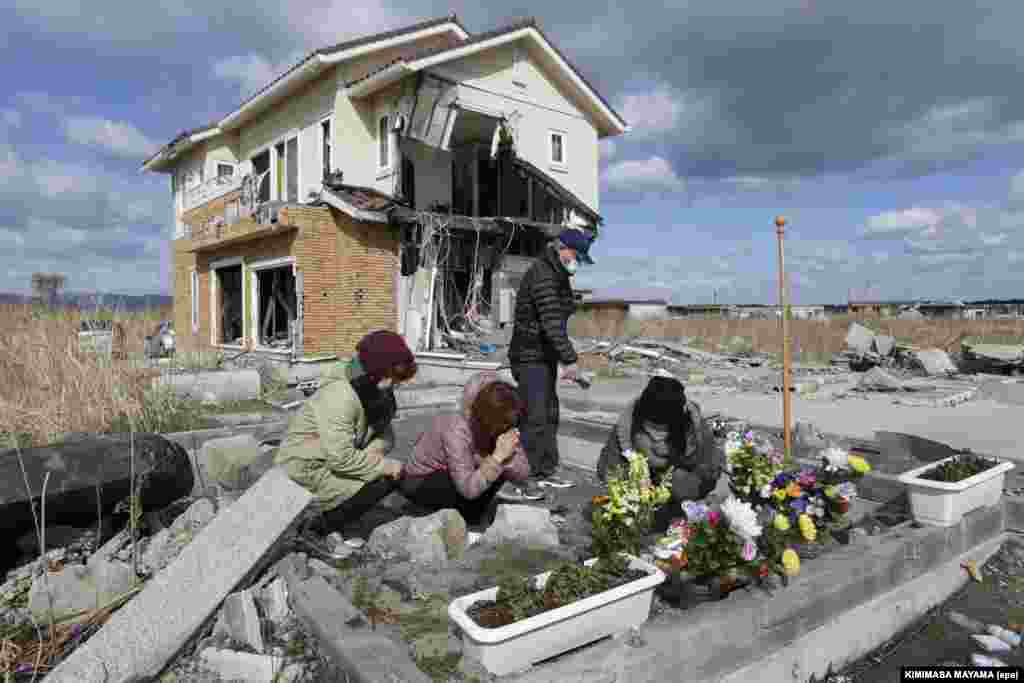 Чиёко Хирата молится по своим родителям у их разрушенного дома в Намиэ, в 5 километрах от АЭС. Фотография&nbsp;сделана 11 марта 2014 года. Дом самой Чиёко тоже частично разрушен. Он на заднем плане&nbsp;