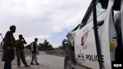 Afghan security forces inspect the site of a roadside bomb blast that targeted a police vehicle in eastern Afghanistan in April.