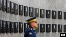 Një pjesëtar i FSK-së qëndron pranë një memoriali në Reçak. Fotografi nga arkivi