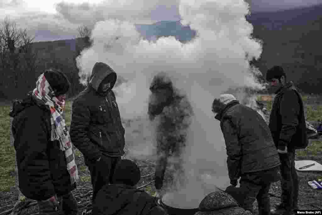 Një grup refugjatësh nga Afganistani gatuajnë në malet përreth qytetit Bihaq të Bosnjës. 