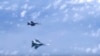 Винищувач Су-27 російських ВПС (знизу) маневрує на тлі військового літака НАТО F-18 над Балтійським морем, архівне фото, 2019 рік