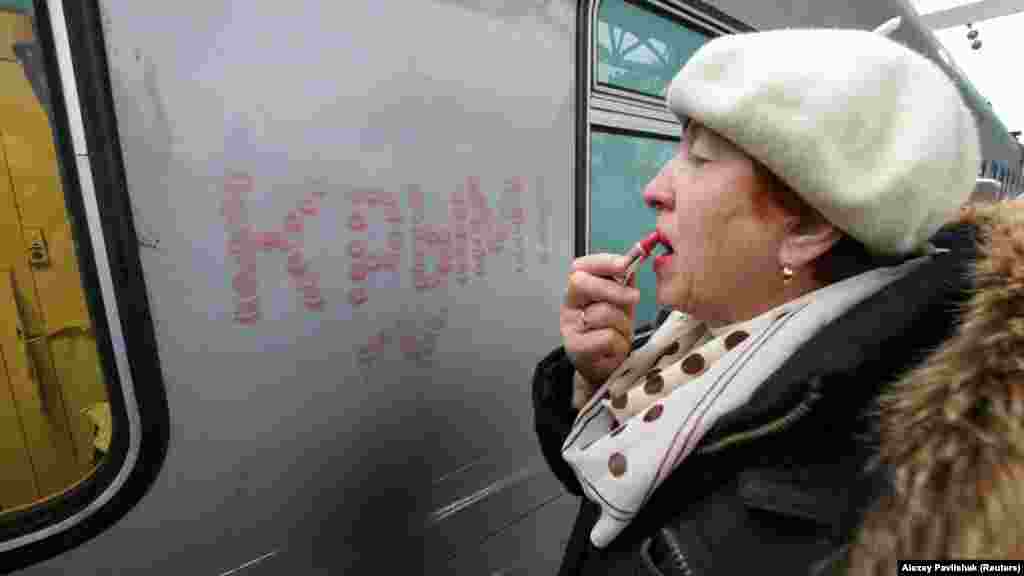 A woman in Sevastopol writes the word &quot;Crimea&quot; in lipstick on a railway carriage upon the arrival of the first direct train from Saint Petersburg via the Kerch Strait Bridge on December 25. (Reuters/Alexey Pavlishak)