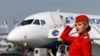 Az Aeroflot orosz légitársaság egyik utaskísérője pózol egy Szuhoj Superjet 100-as repülőgép előtt