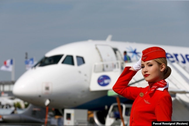 A cabin crew member of Russian carrier Aeroflot poses in front of a Sukhoi Superjet 100 at a photo session at the 51st Paris Air Show in June 2015.