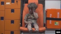 Fotografija dječaka uprljanog prašinom i umazanog krvlju u vozilu hitne pomoći, nakon što je preživio zračni udar u Alepu.