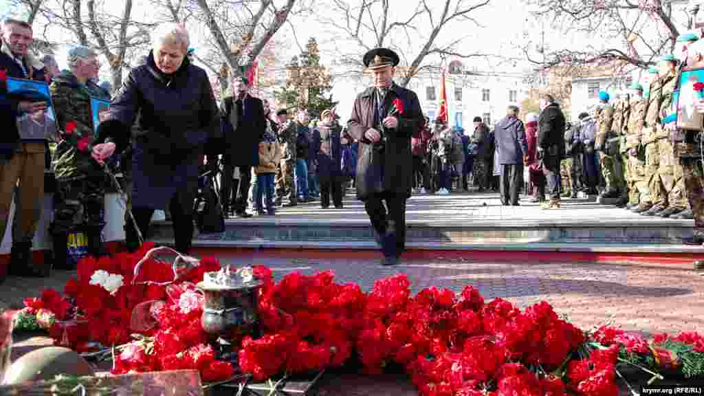 Жінка й офіцер у відставці несуть квіти до меморіалу радянським воїнам із Севастополя, загиблим в Афганістані