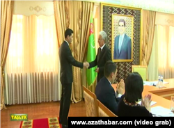 Сердар Бердымухамедов на фоне портрета своего отца получает поздравление с избранием депутатом парламента от Ахалского велаята.