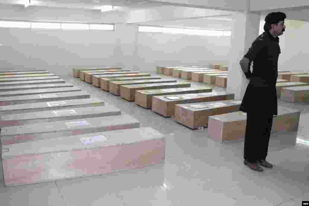 A security official stands guard at a hospital in Abbottabad beside coffins containing the remains of the 47 victims of a Pakistan International Airlines crash. A PIA ATR-42 plane crashed into a mountainside on December 7. Pakistani authorities are investigating the cause of the crash. (epa/Sultan Dogar)