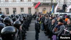 Police stand guard in front of protesters during a demonstration in support of EU integration in front of the parliament building in Kyiv on December 3.