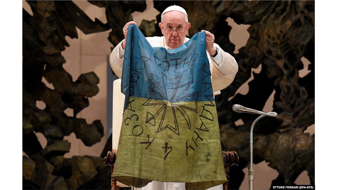 Papa Francisc ține un steag adus de la Bucea, în timpul audienței generale săptămânale. Vatican, 6 aprilie 2022.