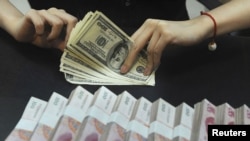 An employee counts U.S. dollars next to Renminbi yuan banknotes at a bank in Anhui Province in September.