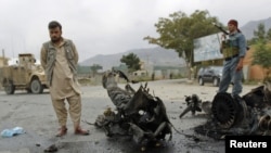 FILE: A policeman and a civilian stand at the site of a bomb attack outside the government of Parwan province in Charikar