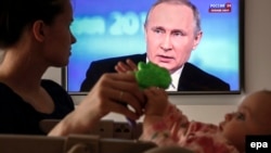 Мать с ребенком смотрят пресс-конференцию Владимира Путина 
